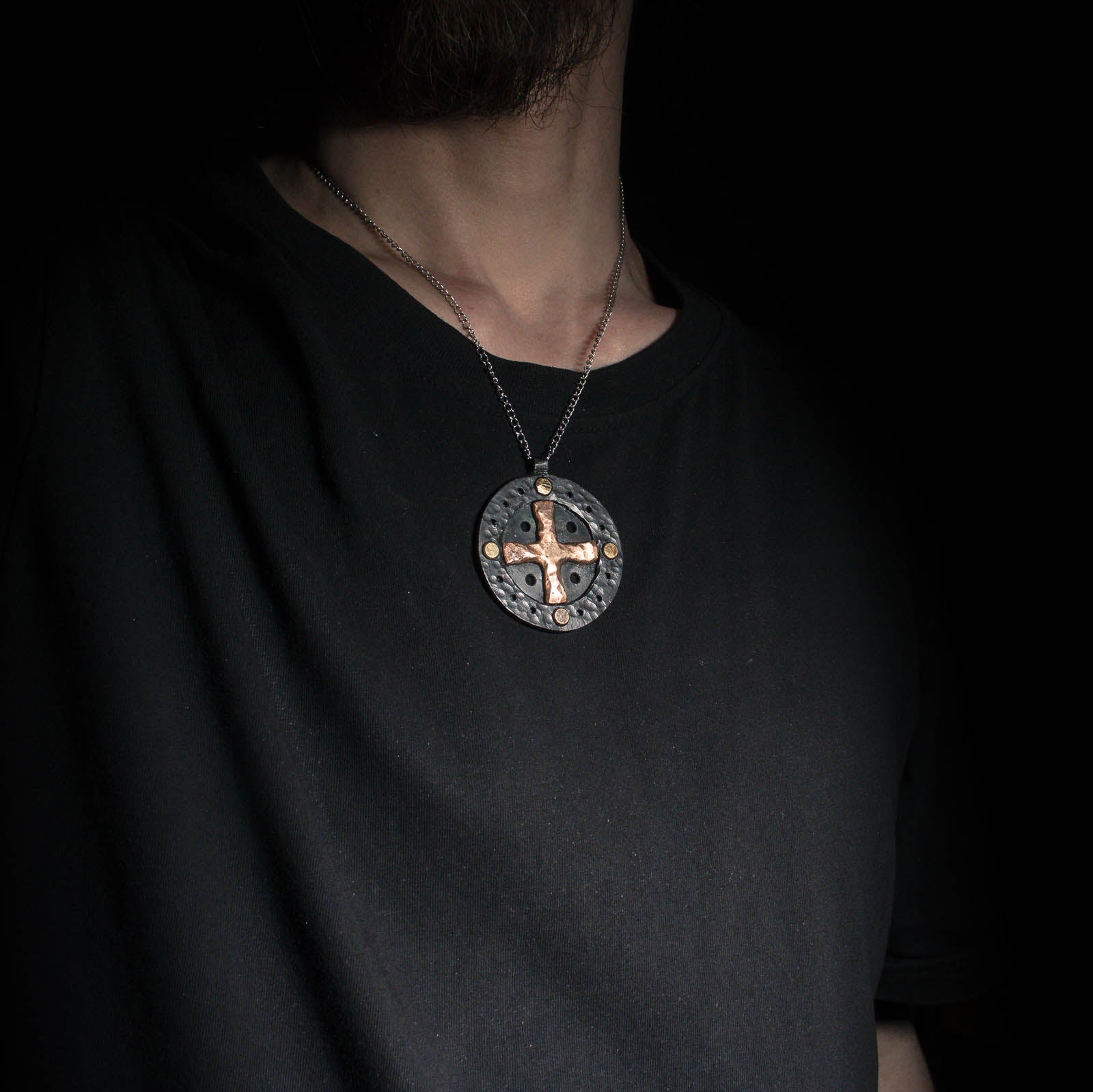 model wearing a sun cross pendant in iron and bronze