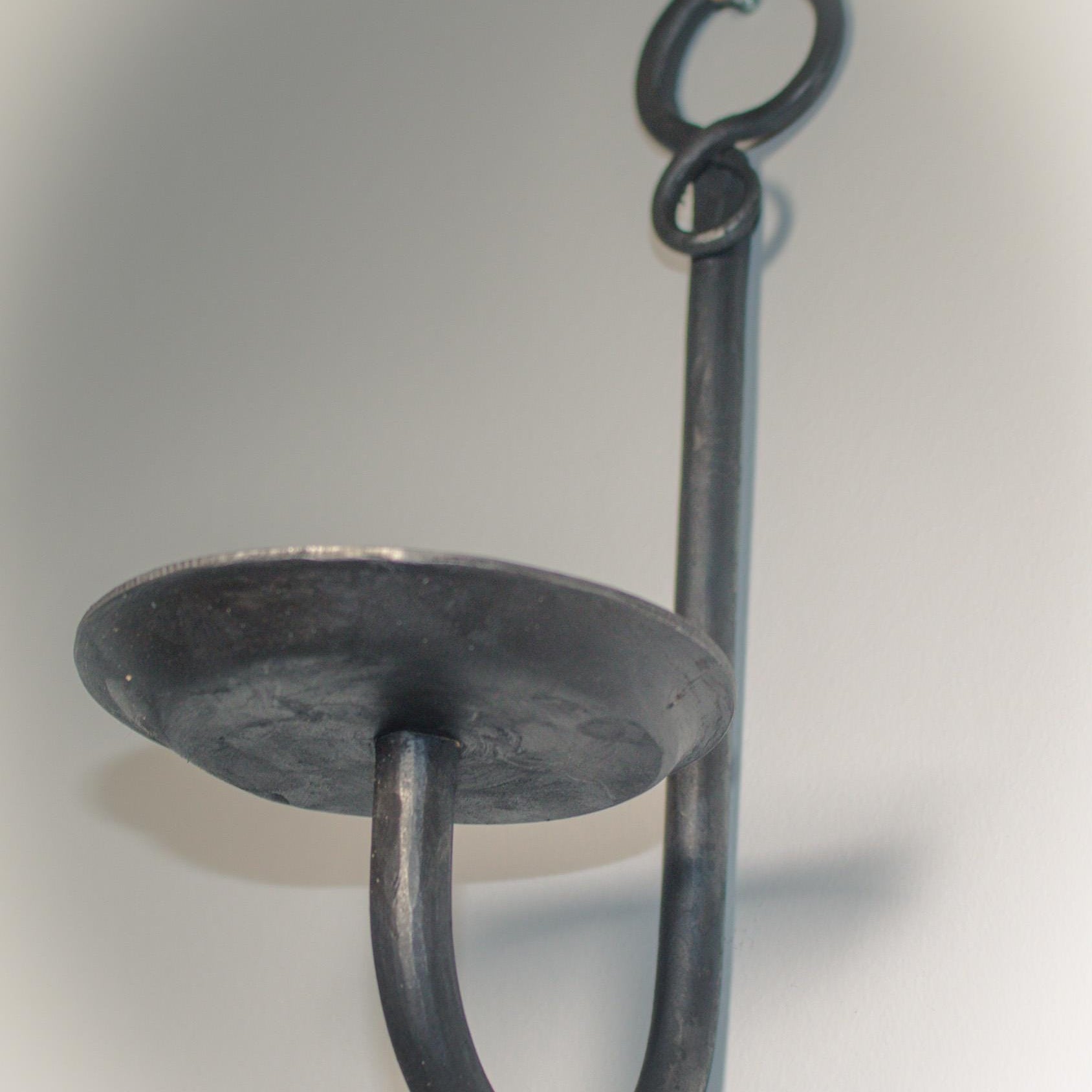 Minimalist blacksmith-made candle holder with a gem detail, designed for wall use.