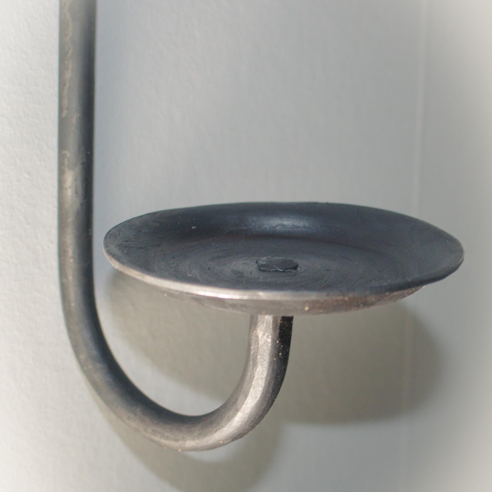 Wall-mounted candle holder with a simple yet sophisticated loop and gem accent.