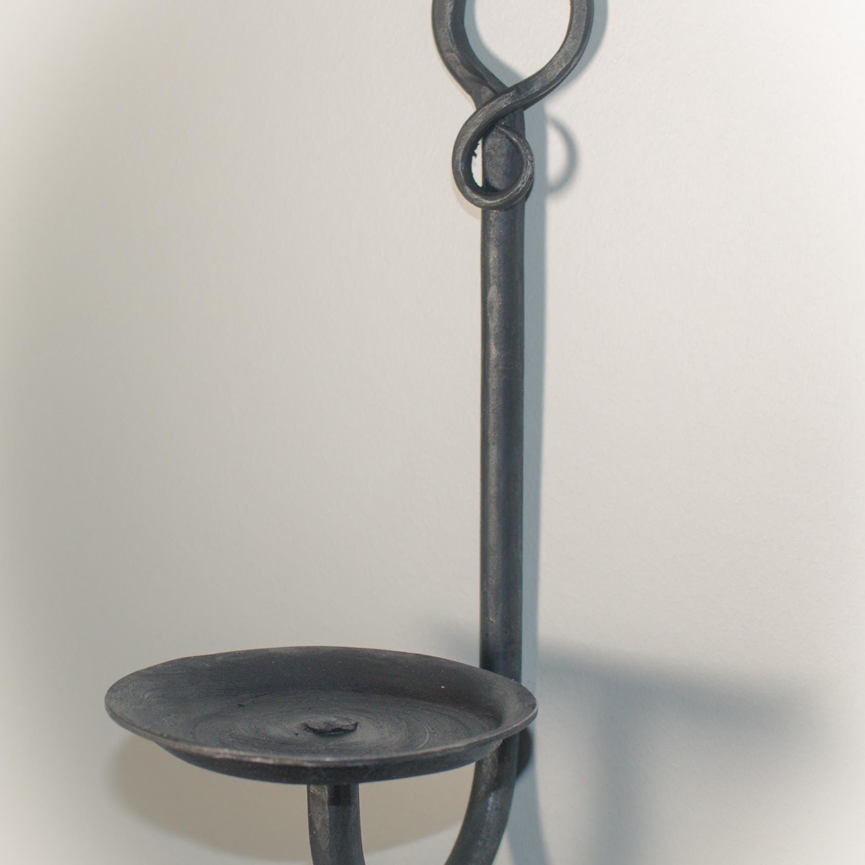 Artisan-made wall-mounted candle holder with a loop design and gemstone detail