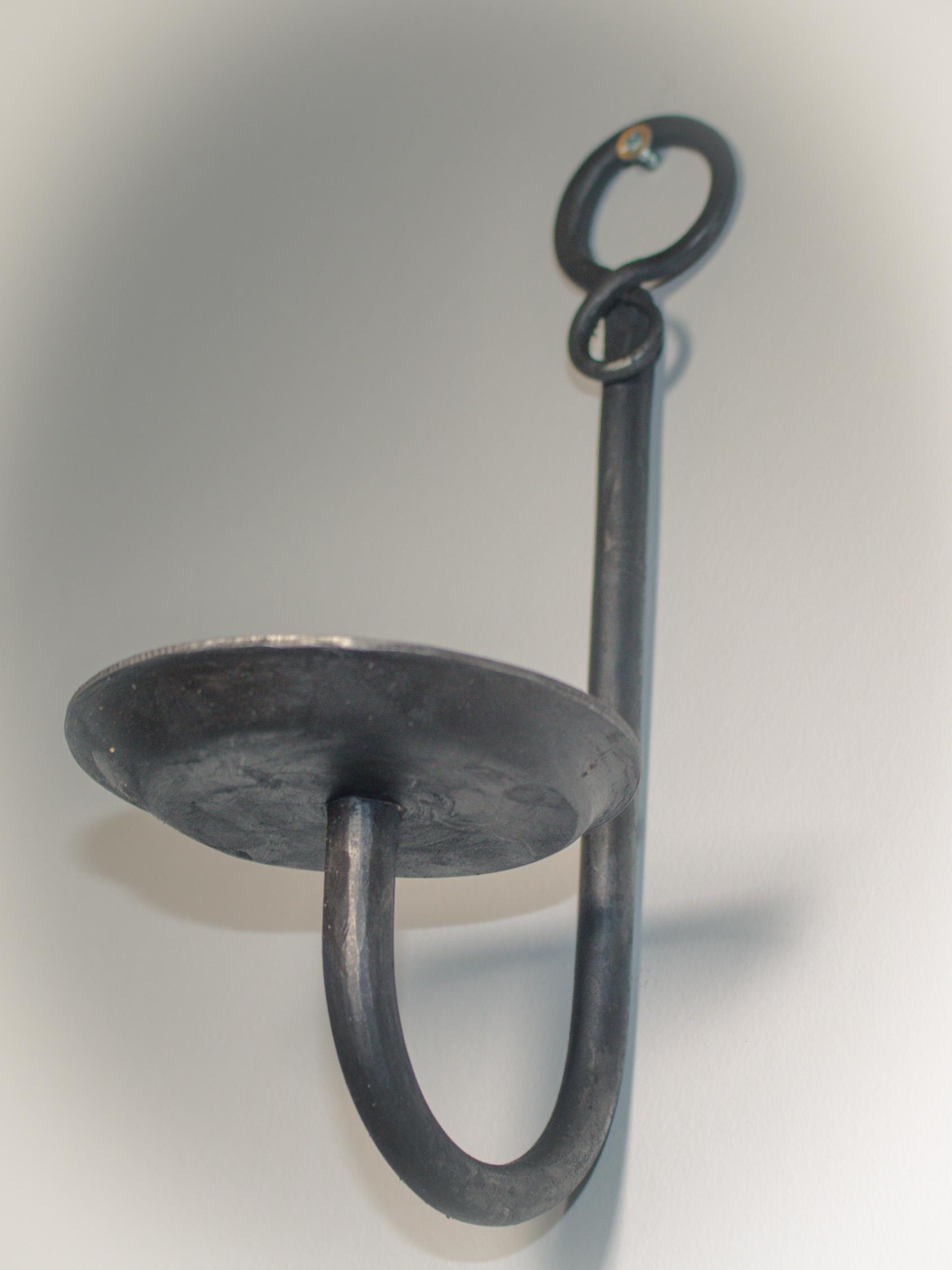 Minimalist blacksmith-made candle holder with a gem detail, designed for wall use.