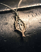 Artisanal Norse jewelry piece featuring a protective bindrune symbol, captured in dramatic lighting